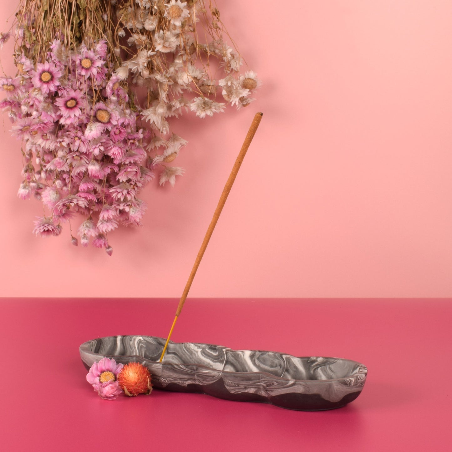 Black and white marbled jesmonite incense holder holding a stick of incense