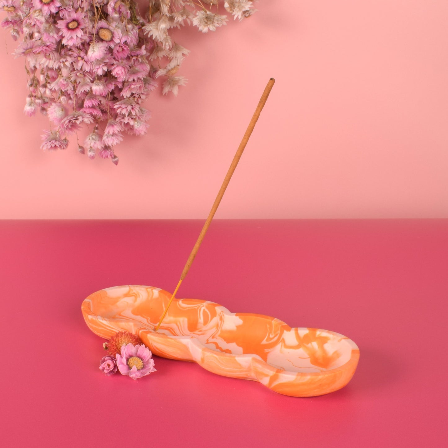 Orange and pink marbled jesmonite incense holder holding a stick of incense